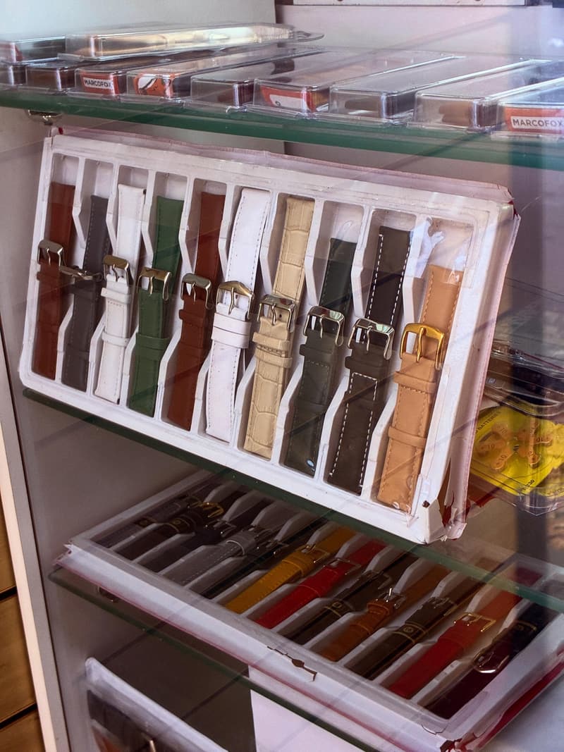 Vitrine de vidro com pulseiras de relógio em couro branco, verde, caramelo e cinza